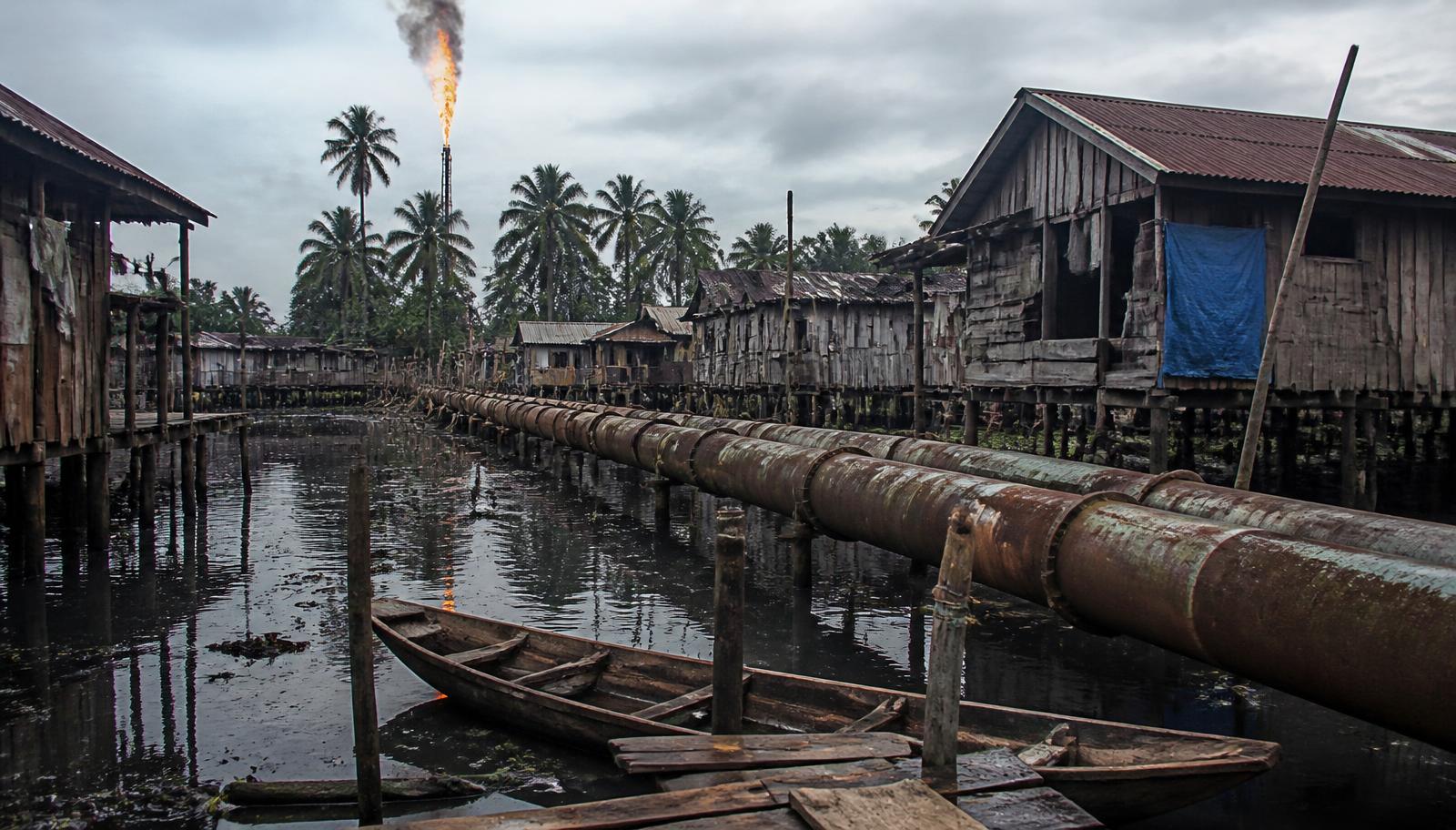 A riverine settlement threaded by pipeline and flare — the everyday geography of internal colonialism.