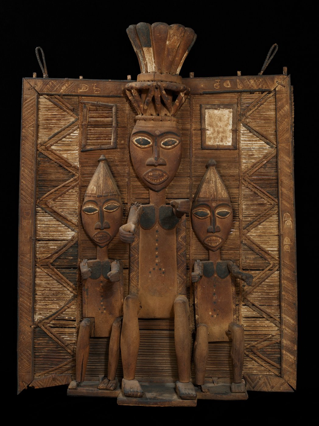 A Kalabari ancestral memorial screen: a central figure in a bladed crown between two attendants